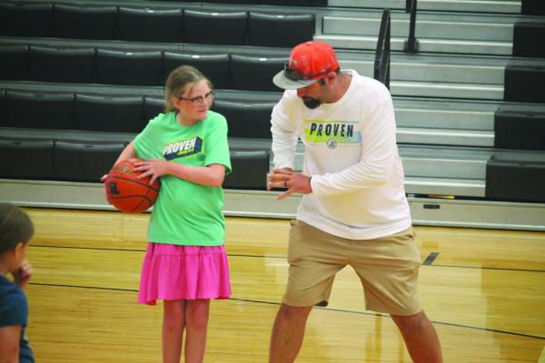 Monitor Photo/Russell Slaton Kemp High School assistant football coach Kevin McCombs (right) teaches his daughter Madi a basketball move at the July 6 skills camp, for which sessions started June 8.