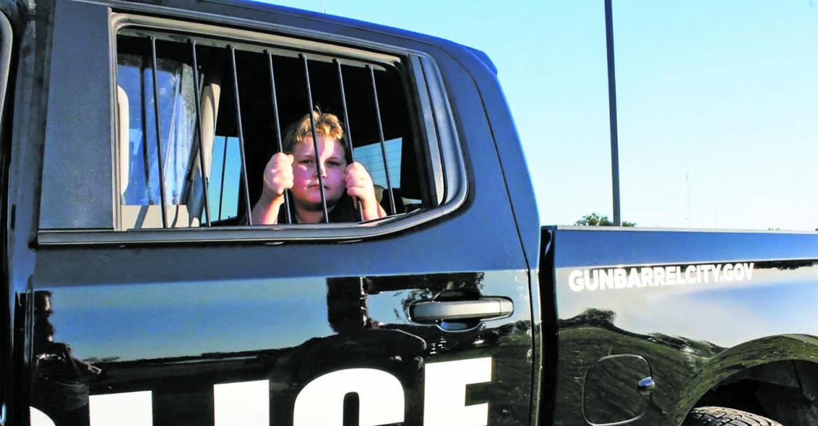 Monitor Photo/Carla Gray National Night Out is a time when local police and firefighters provide community fun and information. The Gun Barrel City police and fire departments provided hot dogs, drinks and snow cones along with showing off the equipment that is used everyday.  Kingston Parks gets the experience of sitting in the backseat of a Gun Barrel City Police vehicle Oct. 6.